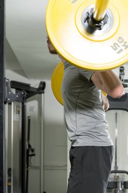 Atletik bir adamın omuzlarına ağır halter