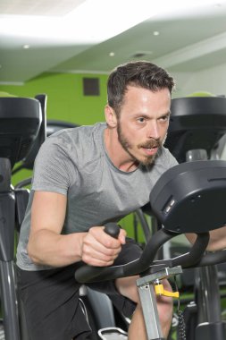 Bir spor salonunda sabit bir bisiklet içinde çalışma dışarı adam