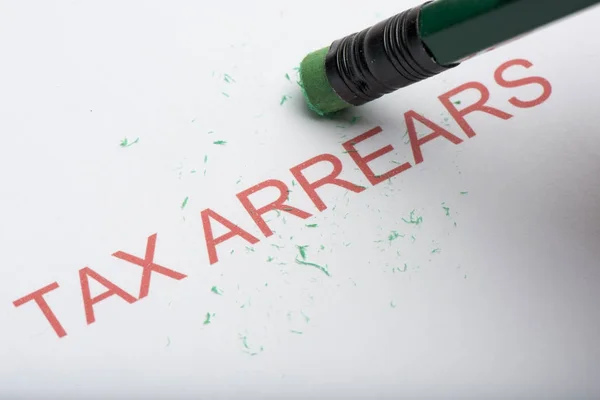 Pencil Erasing the Word 'Tax Arrears' on Paper — Stock Photo, Image