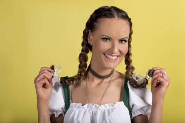 Dirndl örgüler sarı arka plan üzerinde tutan güzel Bayan