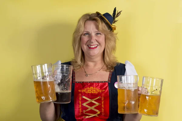 Dame in de traditionele Duitse kleding houden vier mokken van bier — Stockfoto