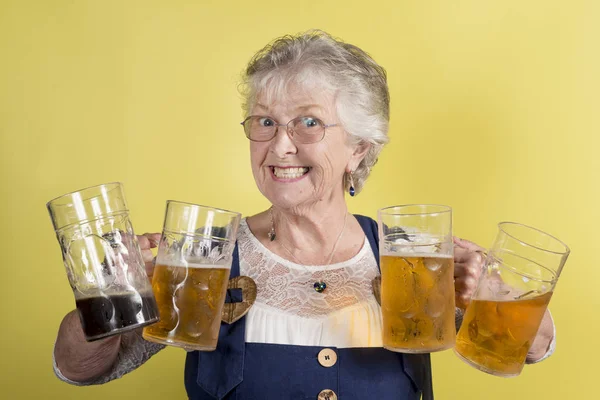Grijnzende oude dame houdt van vier grote Crystal mokken met bier — Stockfoto
