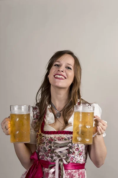 Dirndli-viselő pincérnő gazdaság két hatalmas kristály bögre sört — Stock Fotó