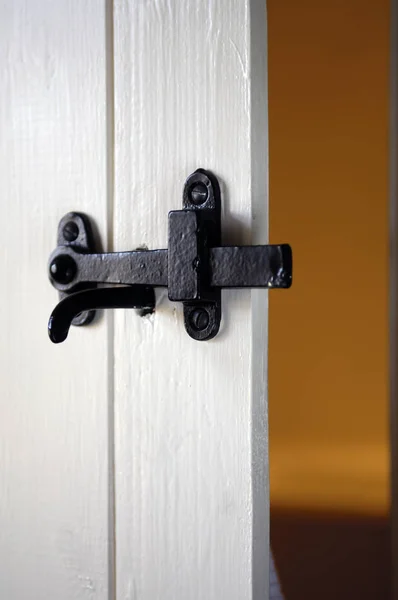 Trava de ferro preto na porta de madeira branca — Fotografia de Stock