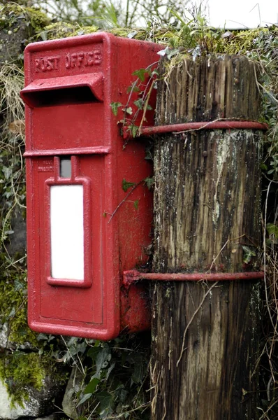 Boîte aux lettres en métal rouge attachée à un poteau en bois — Photo