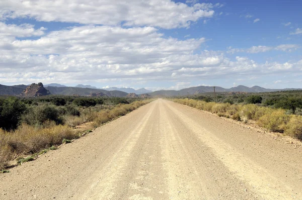 Wüste unbefestigte Straße mit Gebirgskette am Horizont — Stockfoto