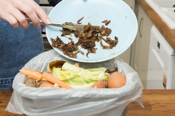 Resterna från plattan kastas in Bin fylld med matrester — Stockfoto