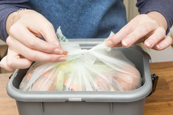 Atar una bolsa de plástico llena de restos de comida en la papelera — Foto de Stock