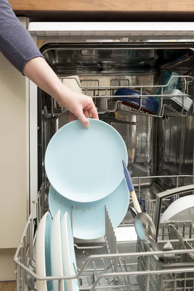 La mano della donna scivola in un piatto nello scaffale della lavastoviglie — Foto Stock