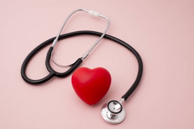 Kırmızı kalp ve pembe bir arka plan üzerinde bir stetoskop