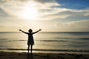 Sahilde uzanmış kolları olan kadın silüeti