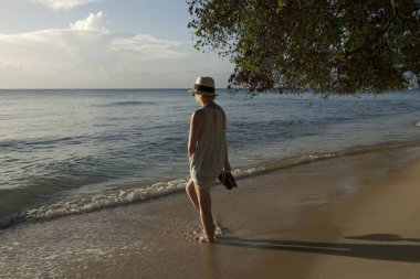 Beach, bakan okyanus ve parmak arası terlik tutan kadın