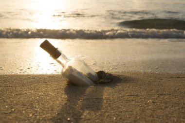 Not bir şişe kum okyanus arka planda ile yarı gömülü