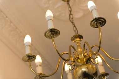 Tavan arka planda ile yanan ampuller ile pirinç avize