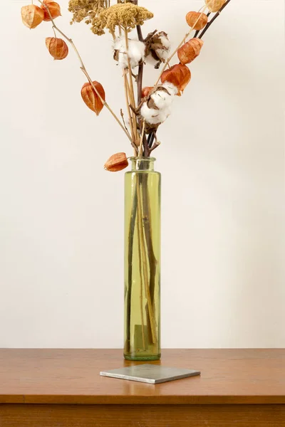 Vaza cilindrică cu flori uscate și coaster pătrat pe lemn — Fotografie, imagine de stoc