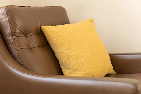 Oreiller carré jaune sur un fauteuil en cuir marron — Photo
