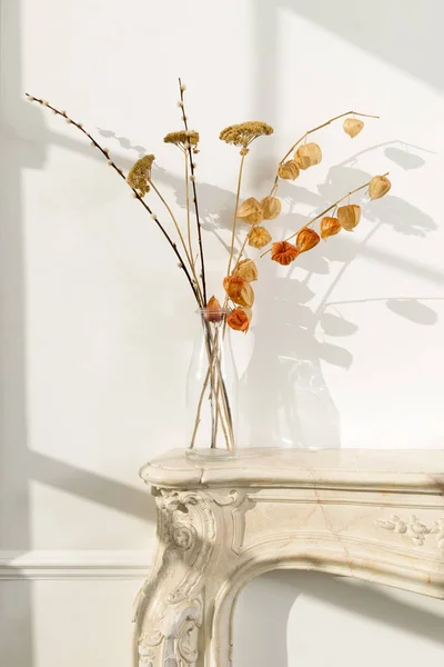 Clear Glass Vase with Wilted Flowers on a Fireplace Stock Image