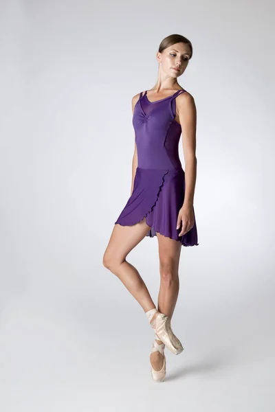 Балерина в фиолетовом трико, изолированном в сером фоне — стоковое фото