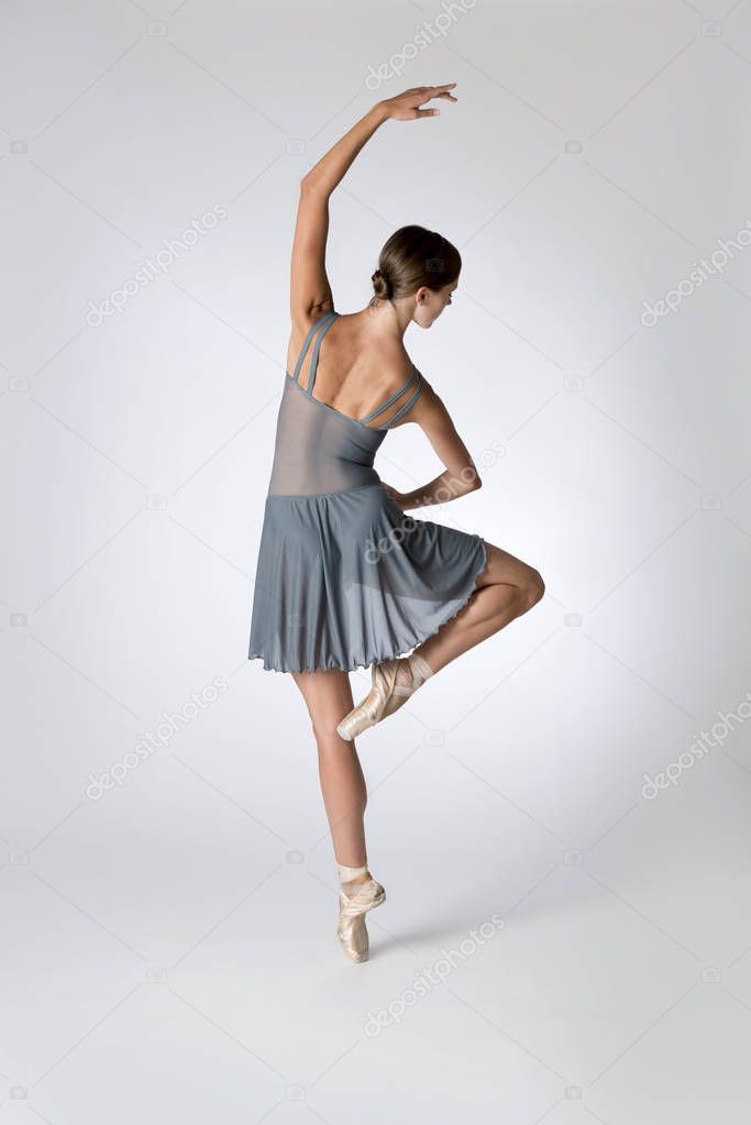Back View of Ballerina Dancing on a Gray Backgroiund