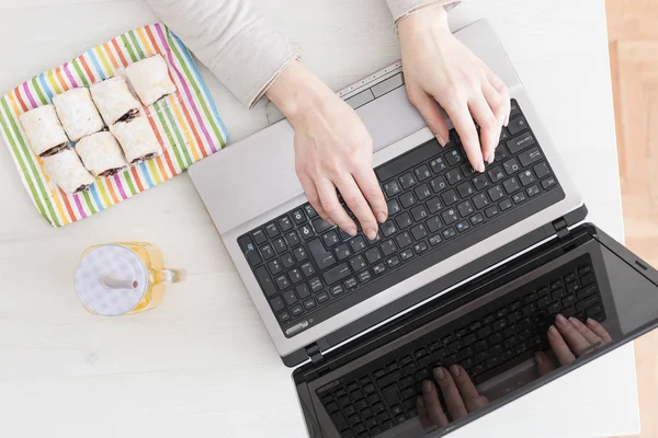 Overhead van de handen typen op Laptop met voedsel aan kant — Stockfoto