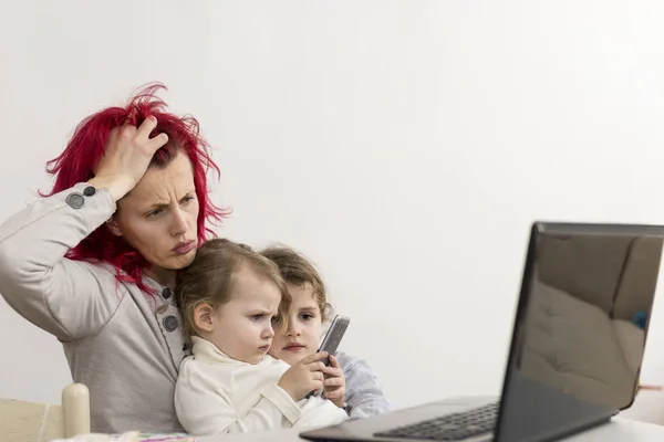 Working Mother Looking Exhausted with Kids on Lap Using Smartpho