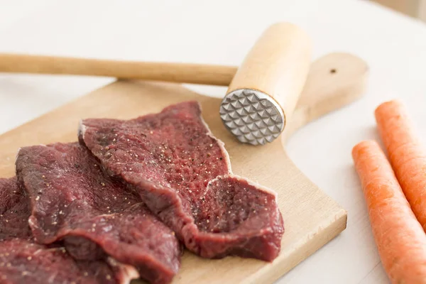 Close-up de fatias de carne crua temperadas na placa de corte de madeira — Fotografia de Stock