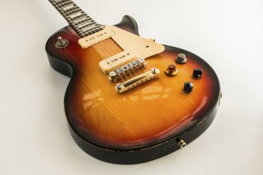 Beyaz bir arka plan üzerinde kuvvetli güneş ışığı renginde elektro gitar