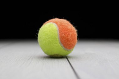 Yeşil ve turuncu renkli tenis topu karanlık bir arka plan ile ahşap bir yüzeye