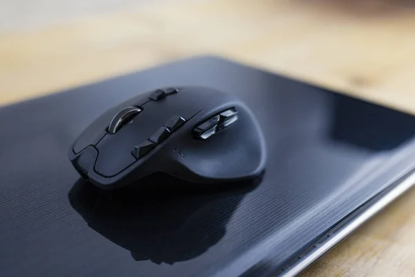 Black gaming mouse on a closed laptop computer