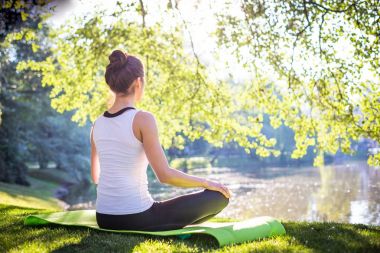 genç kadın meditasyon yoga halı sabah Parkı Gölü, egzersiz Street kavramı üzerinde otururken  