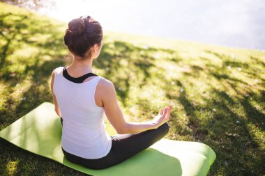 genç kadın meditasyon yoga halı sabah Parkı Gölü, egzersiz Street kavramı üzerinde otururken  
