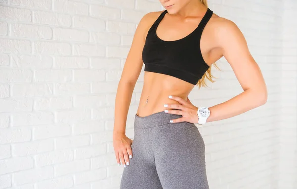 Sport vrouw poseren in photostudio over bakstenen muur. Fitness motivatie — Stockfoto