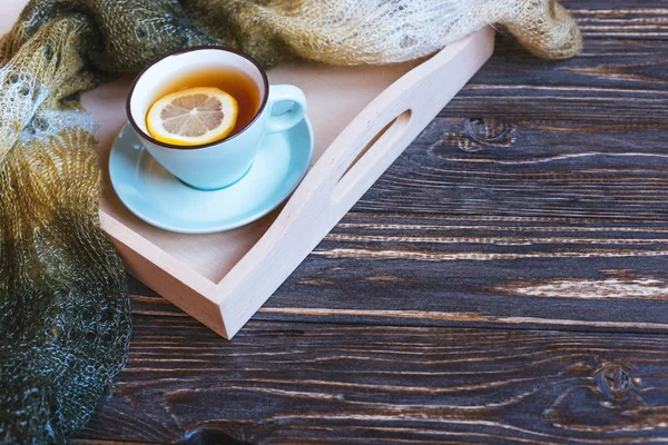 Heißer Tee und blaue Tasse mit Zitrone auf Holzhintergrund - saisonales Entspannungskonzept. — Stockfoto