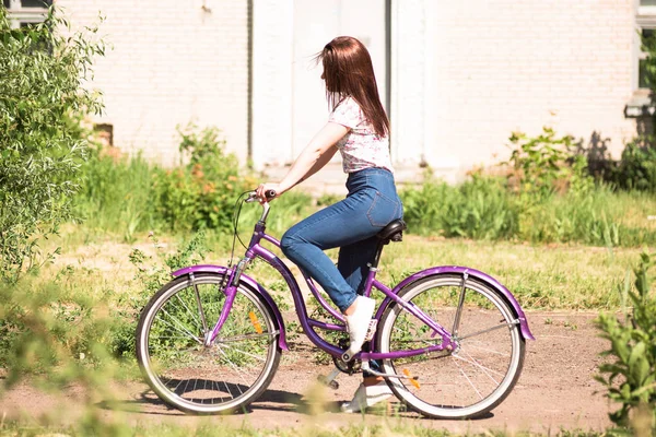 Щаслива молода дівчина їде на велосипеді на літньому парку. Щасливий відпочинок у місті. Красива жінка, сонячний день — стокове фото