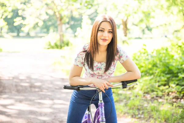 Happy pretty young girl bicycling on summer park. Happy relax time in city. Beautiful woman, sunny day — Stock Photo, Image