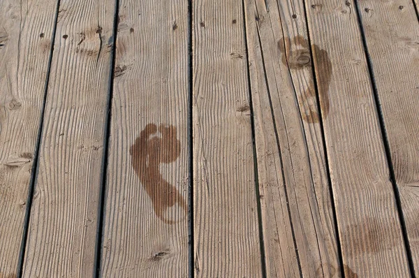 A fából készült padló nedves lábnyomok. Stock Fotó
