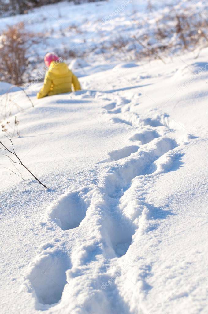 Footprints in snow leads to the little girl.