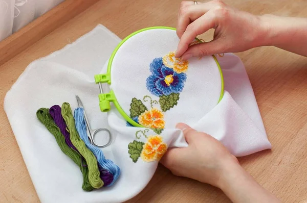 Las manos femeninas están bordando flores en el lienzo. Técnica de punto de cruz . — Foto de Stock