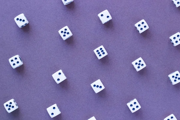 Gaming white dice pattern on purple background in flat lay style. Concept with copy space for games, game board, role playing game, risk, chance, good luck or gambling. Toned image top view. Close-up.