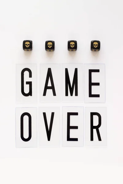 GAME OVER text and gaming dice with image skull on white background. Concept for banners, web pages, games, presentation. Top view.