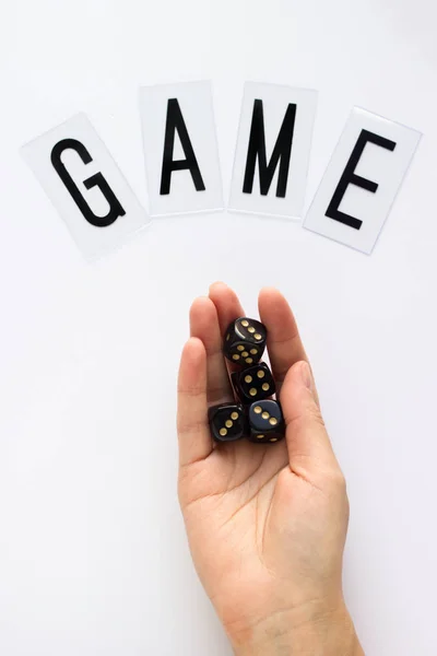 Female hand holds gaming dice on white background. Concept with GAME text for presentation, banners, game board, role playing game, risk, chance, good luck. Top view image. Close-up.