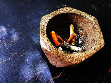 Kül tablası şeklinde altıgenler, içinde sigara izmaritleri olan ahşap bir masaya yerleştirilmiş..