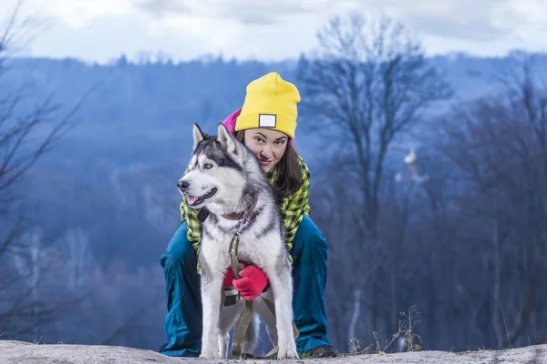 Mädchen sitzt mit Husky-Hund in den Bergen — Stockfoto