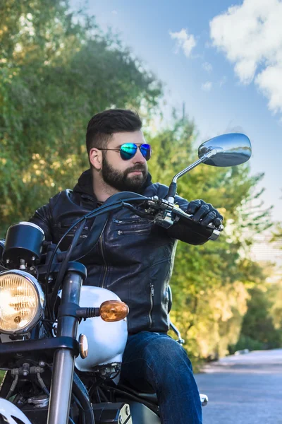 Байкер у шкіряній куртці та сонцезахисних окулярах сидить на мотоциклі — стокове фото