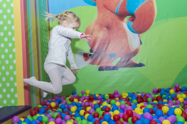 Chica saltando en las bolas de colores. jugando en el parque parque infantil . — Foto de Stock