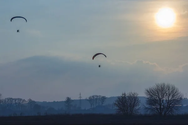 Paramotor-Segelflugzeug fliegt bei Sonnenuntergang am Himmel über wunderschöner Landschaft — Stockfoto