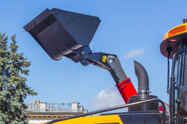 Bir ekskavatör kova üzerinde mavi gökyüzü kaldırdı. Yaz