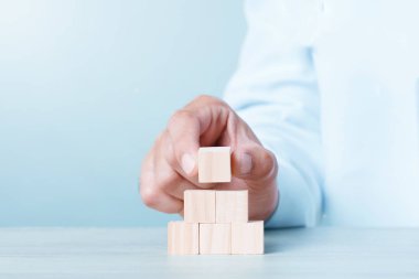 Six Wood Block Cubic stack with Hand on table Blue Tone Background. Free Copy Space.