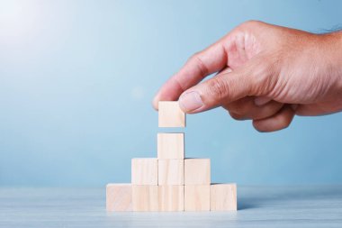 Wood Block Cubic stack with Hand on table Blue Tone Background. Free Copy Space.
