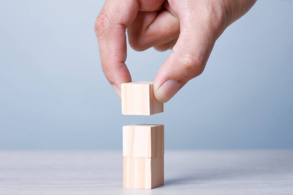 Three Wood Block Cubic stack with Hand on table Blue Tone Background. Free Copy Space.